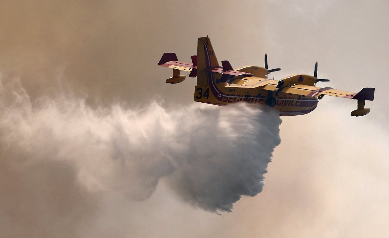 default-387 The plane drops water while flying in a smoky sky.